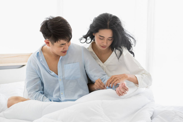 Primo piano colpo di coppia asiatica sul letto insieme, sorridono e si abbracciano con amore
. - Foto, immagini