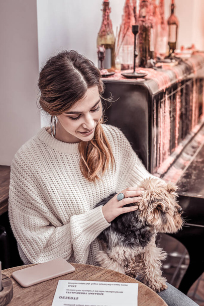 Pretty woman at the restaurant holding her small dog in the lap - Fotografie, Obrázek