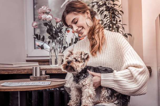 Beautiful young woman holding her yorkshire terrier in lap - Photo, Image