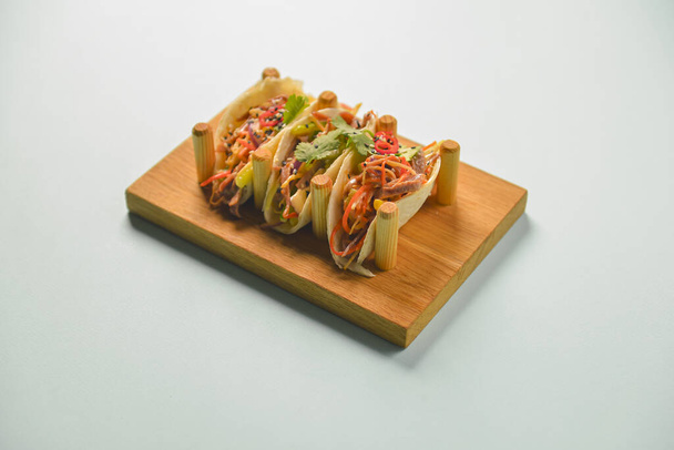 Authentic mexican chicken and beef tacos. Three tacos served on a wooden board over pastel blue mint background. - Фото, зображення