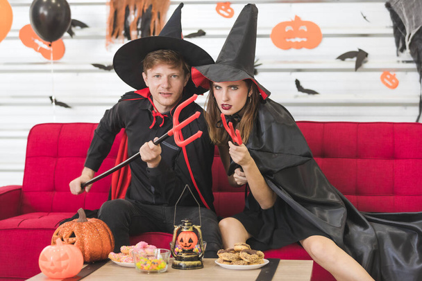 Wicked Caucasian couple dressed up as wizard and witch. In their hands holding a trident, which made them look terrifying, they might go out to do scary things for Halloween. - Foto, Imagem