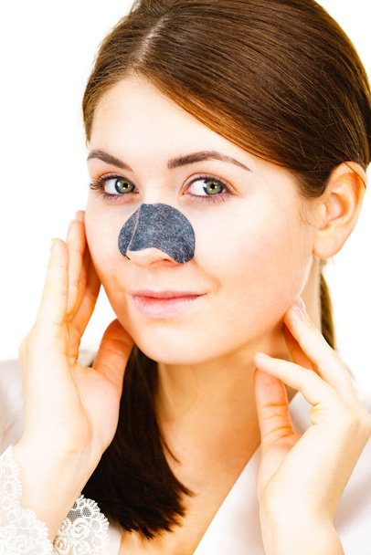 Woman appying clear-up strips on nose, using pore cleansing textile mask, on white. Girl taking care of skin complexion. Beauty treatment. Skincare. - Photo, Image