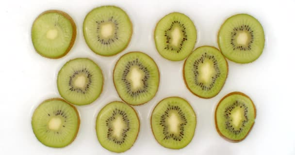 On a white background, sliced kiwis are sprinkled with water. Water drops juicy kiwi - Footage, Video
