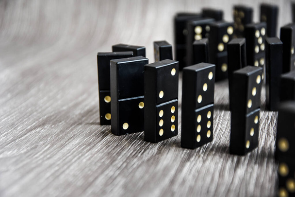 Açık tahta bir masa üzerindeki siyah dominolar art arda dururlar, seçici odak, eski siyah, karton arka planda klasik dominolar. Oyun dominoları konsepti - Fotoğraf, Görsel