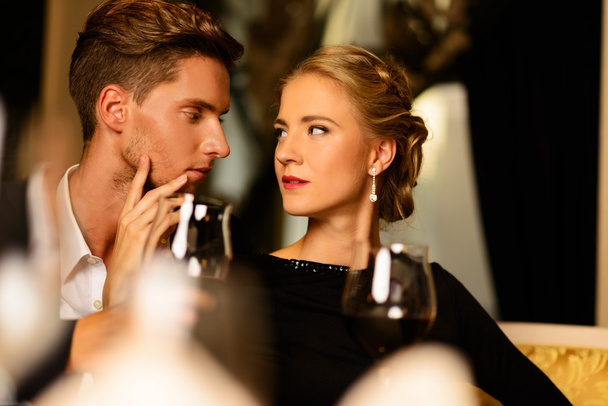 Beau jeune couple avec des verres de vin dans un intérieur de luxe
 - Photo, image