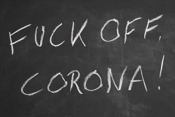 fuck off corona written in chalk on chalkboard - rebellion against covid-19 social distancing measures or resilience against coronavirus crisis - Foto, afbeelding
