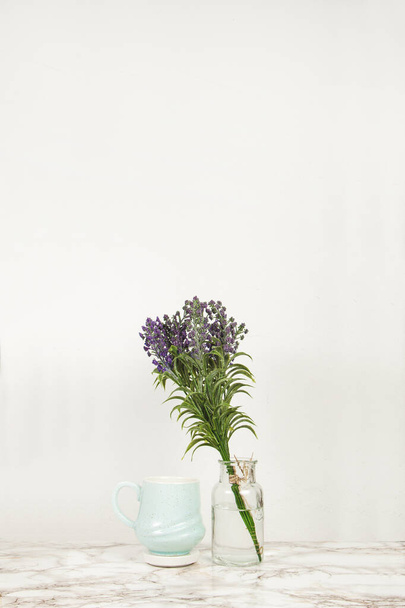Blauwe koffiemok met de vaas van lavendelbloemen op een marmeren tafel - Foto, afbeelding