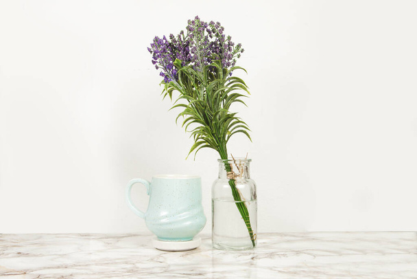 Μπλε κούπα καφέ με το βάζο με τα άνθη λεβάντας σε μαρμάρινο τραπέζι - Φωτογραφία, εικόνα