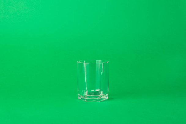 y vidrio facetado vacío sobre un fondo verde
 - Foto, imagen