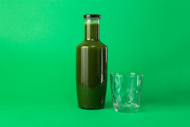 Tuore selleri pinaattimehu lasipullossa ja tyhjä lasi lähellä eristetty vihreällä pohjalla. Terveellinen syöminen Detox mehu ruokavalio
 - Valokuva, kuva