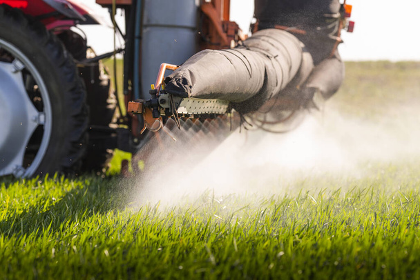 Tractor rociando pesticidas sobre un campo verde - Foto, imagen