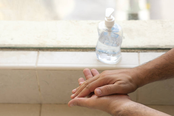 обрізаний знімок людини, що кладе антисептик рукою на руки
 - Фото, зображення