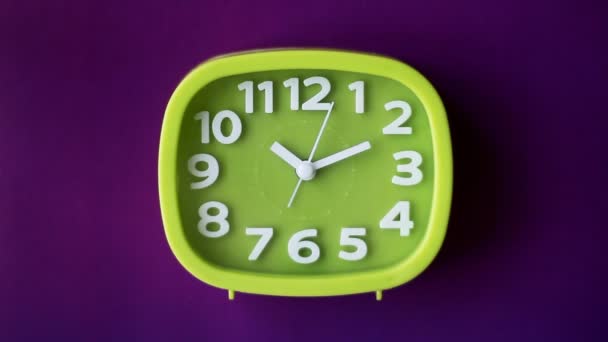 紫色の背景に白い数字と矢印で隔離された緑の時計、リアルタイム - 映像、動画