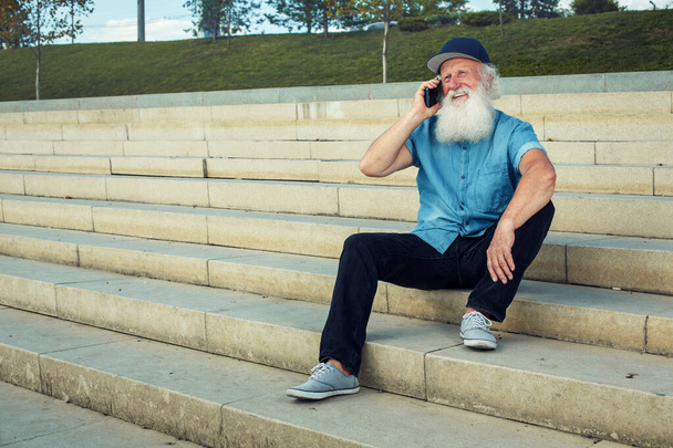 емоційний старший чоловік розмовляє по телефону і сміється надворі
 - Фото, зображення
