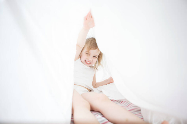 kid girl have fun under blanket on bed. - Photo, Image
