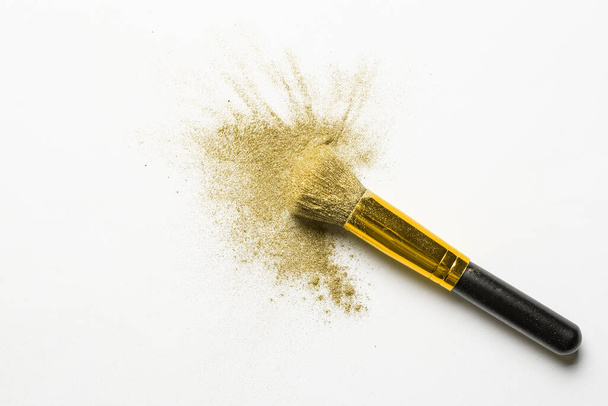 poudre fine dorée éclaboussure et pinceau pour maquilleur ou graphiste en fond blanc
 - Photo, image