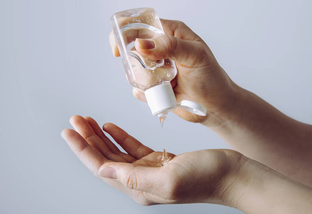 Close up widok kobiety osoby za pomocą małych przenośnych antybakteryjnych środków do dezynfekcji rąk na rękach. - Zdjęcie, obraz
