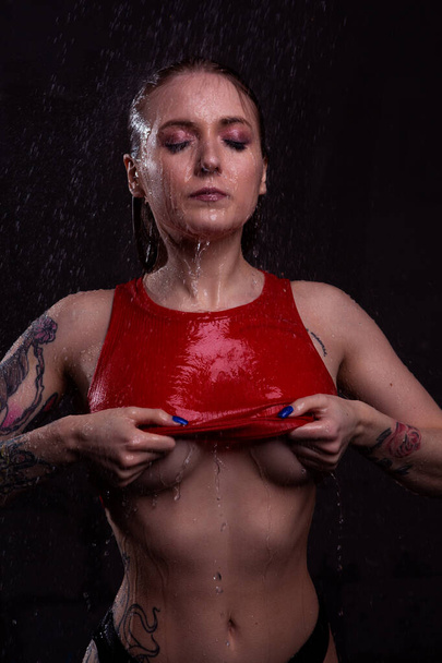 Sexy tattooed blonde girl slowly undresses in the shower Baring her beautiful body - Zdjęcie, obraz