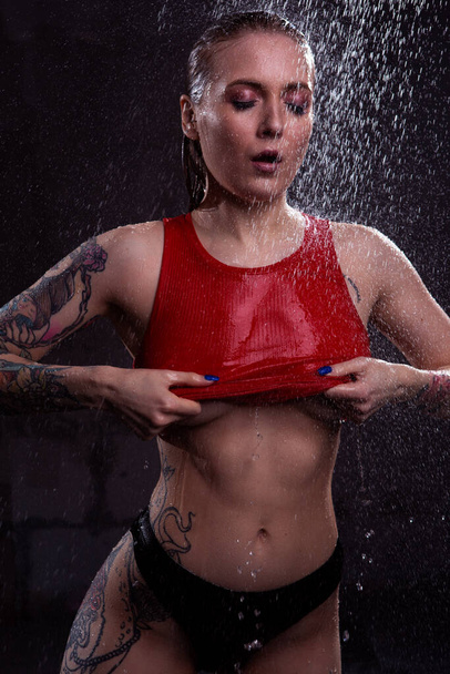 Sexy blonde girl takes off her red underwear under the water jets exposing her Breasts - Photo, Image