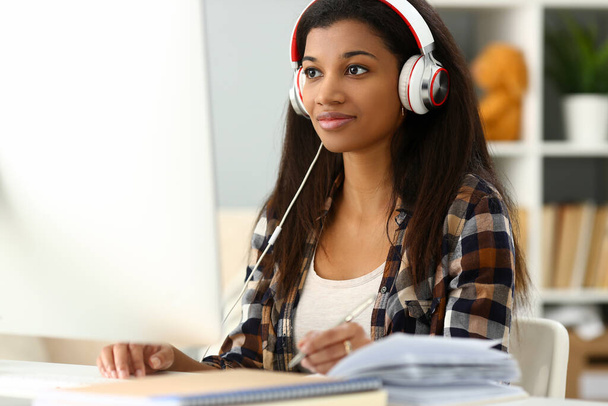 Joven mujer negra con auriculares azules responde cliente
 - Foto, Imagen