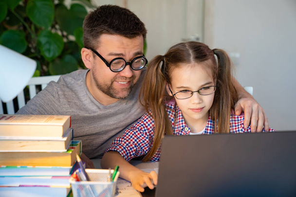 dad in glasses helps daughter lessons on laptop - Photo, Image
