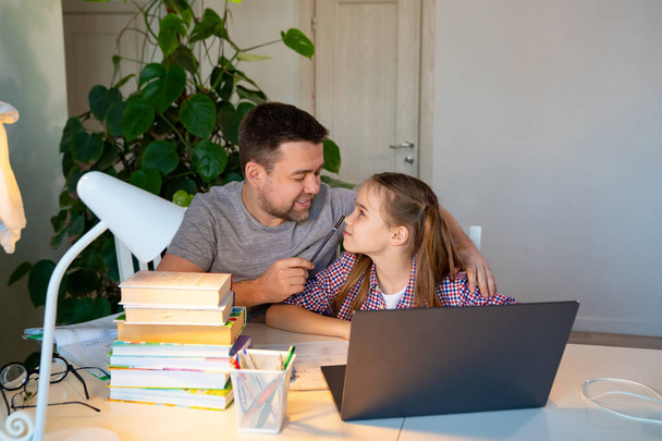 dad helps daughter with online lessons on laptop - Fotografie, Obrázek