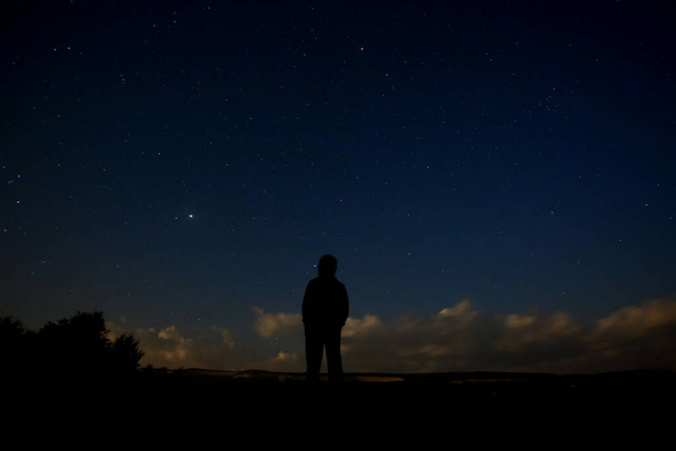 Silhouet van een volk tegen de sterrenhemel 's nachts. - Foto, afbeelding