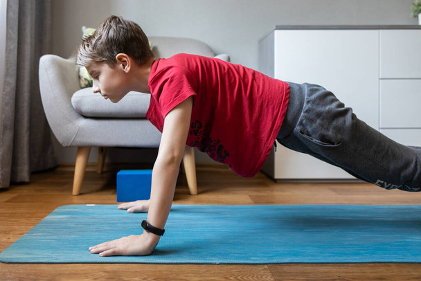 Small boy on yoga mat at home holding plank pose - Foto, Bild