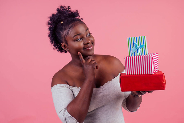 happy afro woman holding gift boxes March 8 in stusio pink background - Fotografie, Obrázek