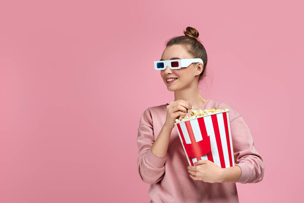 beautiful young woman eating popcorn from bucket - 写真・画像