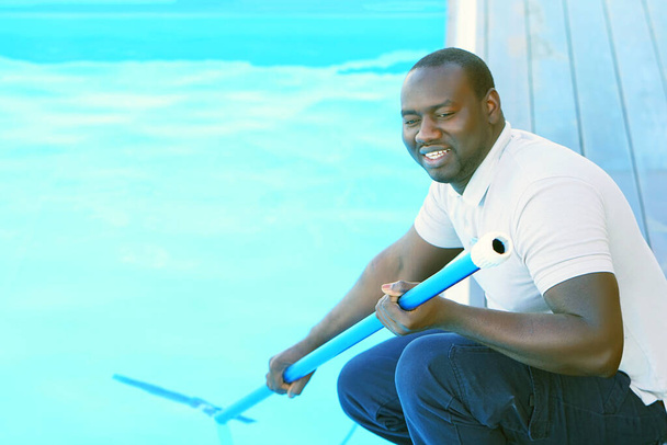 Afrikaanse Zwembadreiniger tijdens zijn werk. Reinigingsrobot voor het reinigen van de bodem van zwembaden. Automatische zwembadreinigers. - Foto, afbeelding