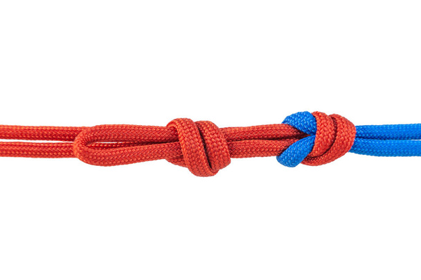 Two red and blue cords are connected . Knot on a cord isolated on a white background . - Photo, Image