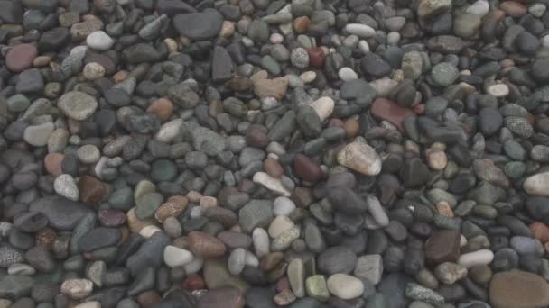 Sea waves roll on pebbles shore during a light storm close up top view - Footage, Video