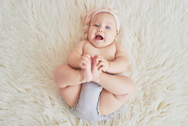 Sweet funny baby on bed in children room. Greeting card, copyspace for your text. Poster for Easter holiday. Congratulations on Mother's Day. Cute baby girl 6 months sitting and crawling - Photo, Image