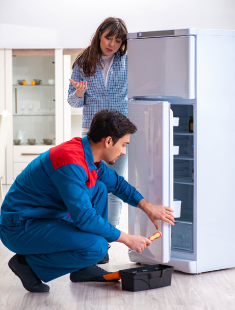 чоловік ремонтує холодильник з клієнтом
 - Фото, зображення