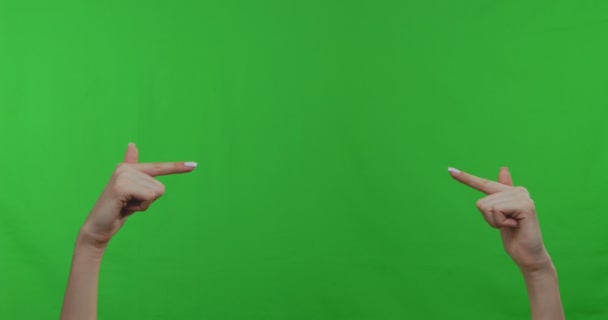 Vrouwelijke handen wijzend naar lege ruimte over groene chromakey achtergrond - Video