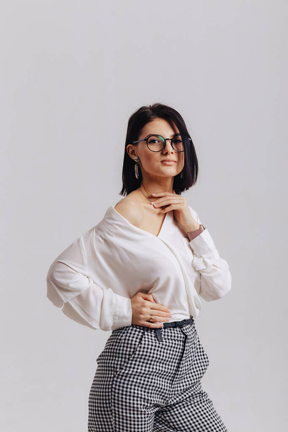 attractive stylish young girl in business clothes posing on light background in studio. concept of stylish clothes and sophistication. simple background. - Φωτογραφία, εικόνα