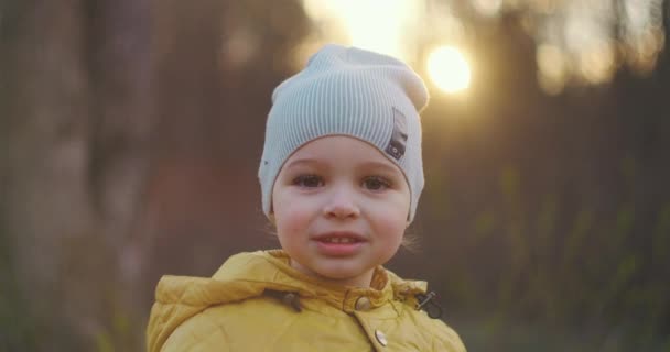 Detailní portrét malého usměvavého chlapce s velkými řasami v čepici a žlutou bundou, který se dívá přímo do kamery. Běloch chlapec 2 roky - Záběry, video