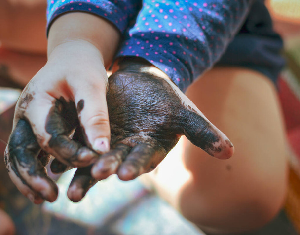 Дитина забруднила руки чорним лаком для нігтів. Долоні дитини в чорній фарбі. Дитячі руки. Дитячі малюнки руками
 - Фото, зображення