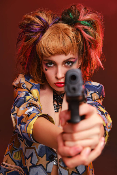 Dangerous girl with bright makeup holds a black gun in her hands. Cosplay character from the movie  - Foto, Imagen