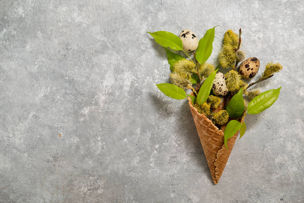 quail eggs and pussy-willow twigs in a waffle cone on a gray background. - Fotografie, Obrázek