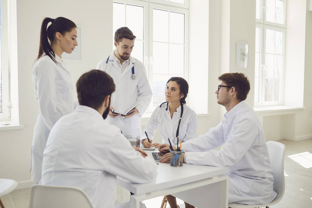 Group of doctors talking sitting at a table in the office of the hospital - 写真・画像