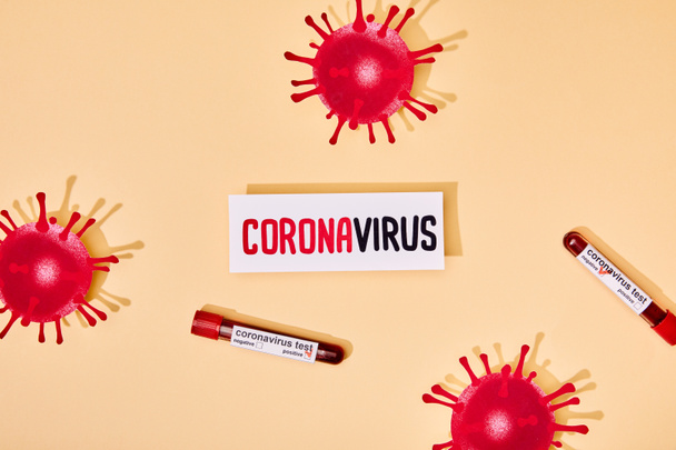 top view of paper with coronavirus lettering near test tubes with coronavirus test and drawn virus on beige  - 写真・画像