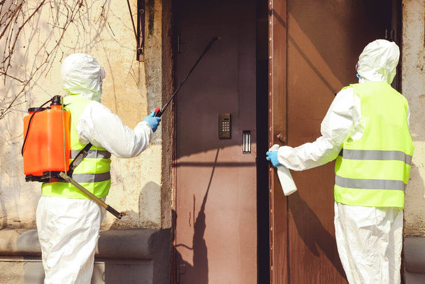 Especialistas en trajes de protección desinfectan la entrada a la casa. Control de la epidemia
. - Foto, imagen