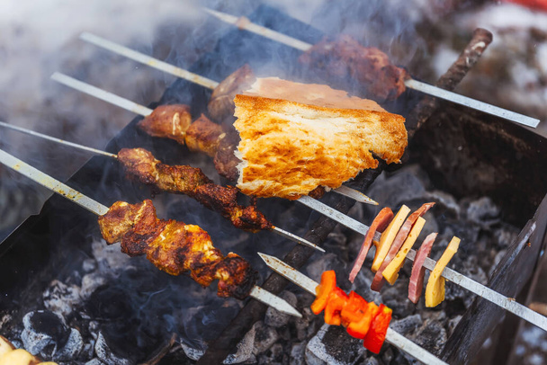 Camping grill z niezwykłym shish kebab ziemniaków kiełbasa ser shish kebab. Przyklej szpikulec i pieczone ziemniaki do grilla. Grill w dymie na zimowym pikniku - Zdjęcie, obraz