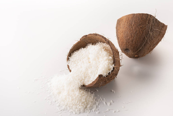 coconut flakes lies in a coconut shell, cut into two halves - Foto, Imagen