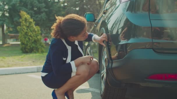 Helpless woman looking at damaged scratched car - Imágenes, Vídeo