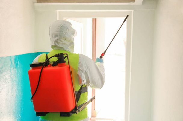 A specialist in a protective suit disinfects the entrance from a coronavirus infection. Epidemic control. - Photo, Image