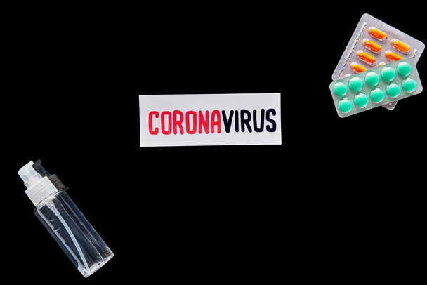 vue du dessus du papier avec lettrage coronavirus près des pilules et désinfectant pour les mains isolé sur noir
  - Photo, image