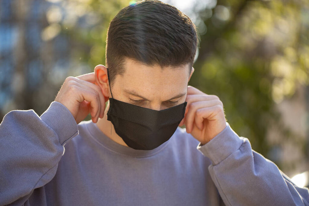 Vírus maszk ember visel arcvédelem megelőzésére a koronavírus. Férfi séta az utcán zöld fa háttér - Fotó, kép
